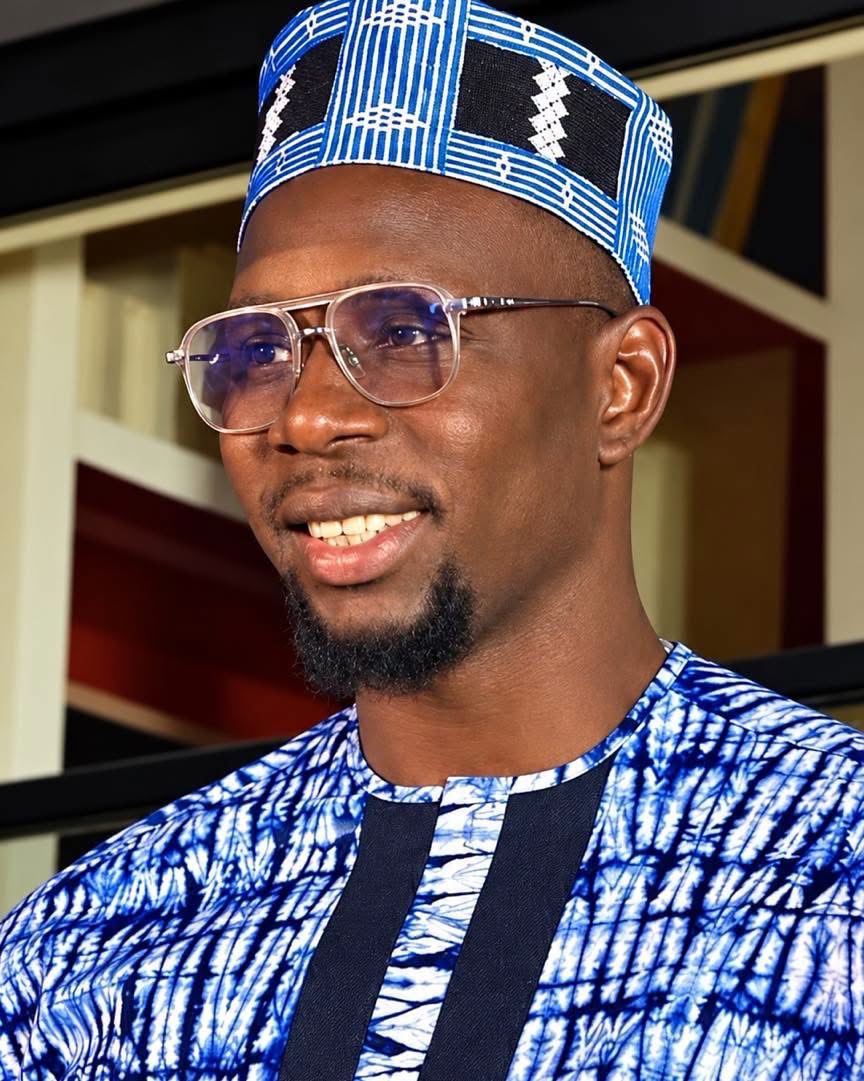 Ablaye Mbaye, official portrait — clear glasses, blue and white traditional attire and matching cap