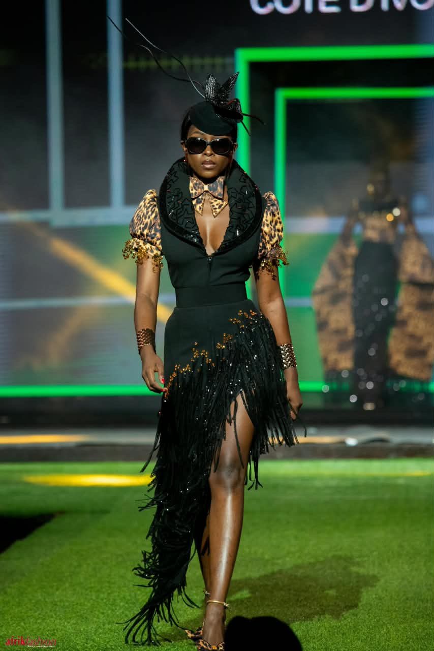Modèle en robe noire à franges et manches léopard sur le podium de l'Afrik Fashion Week