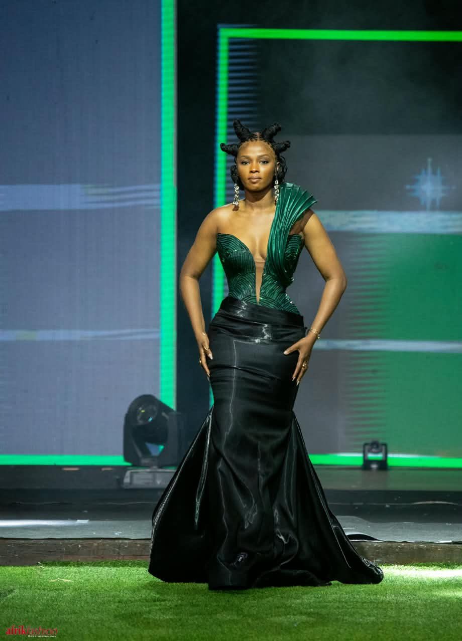 Modèle en robe sirène verte et noire sur le podium de l'Afrik Fashion Week