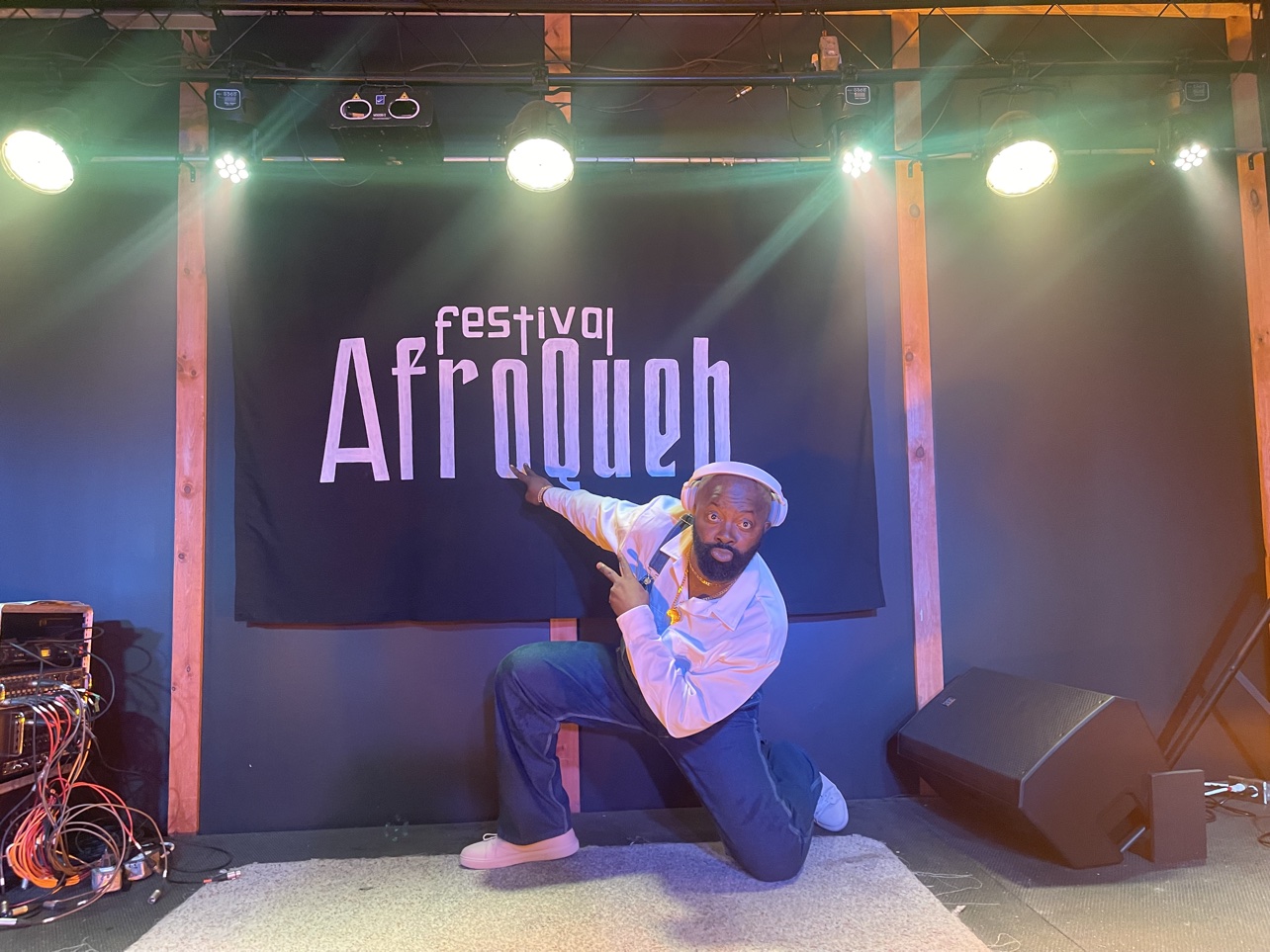 Moïse 1er in front of the banner of the AfroQueb Festival