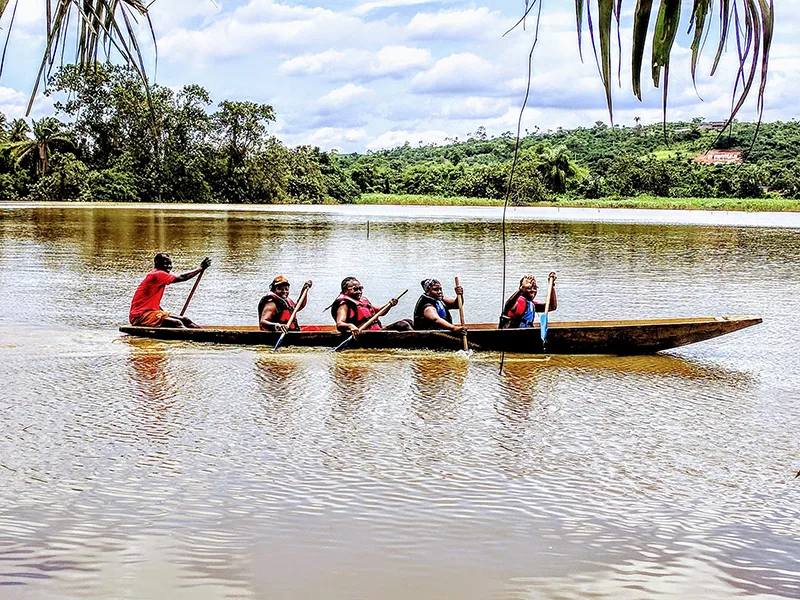 Five paddlers in vests cross the Aghien lagoon in a long pineapple