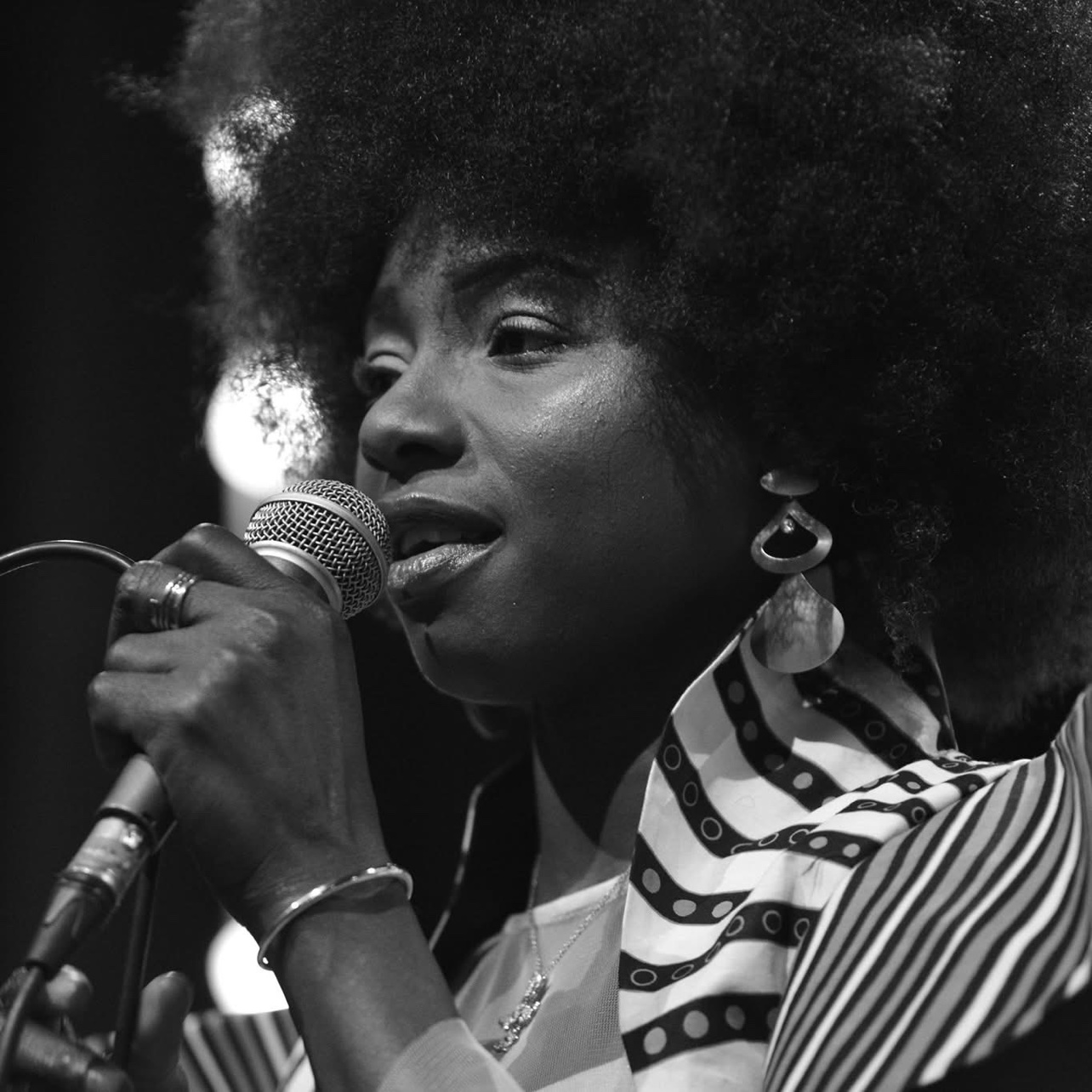 Kandy Guira in concert, at the microphone — black and white photograph