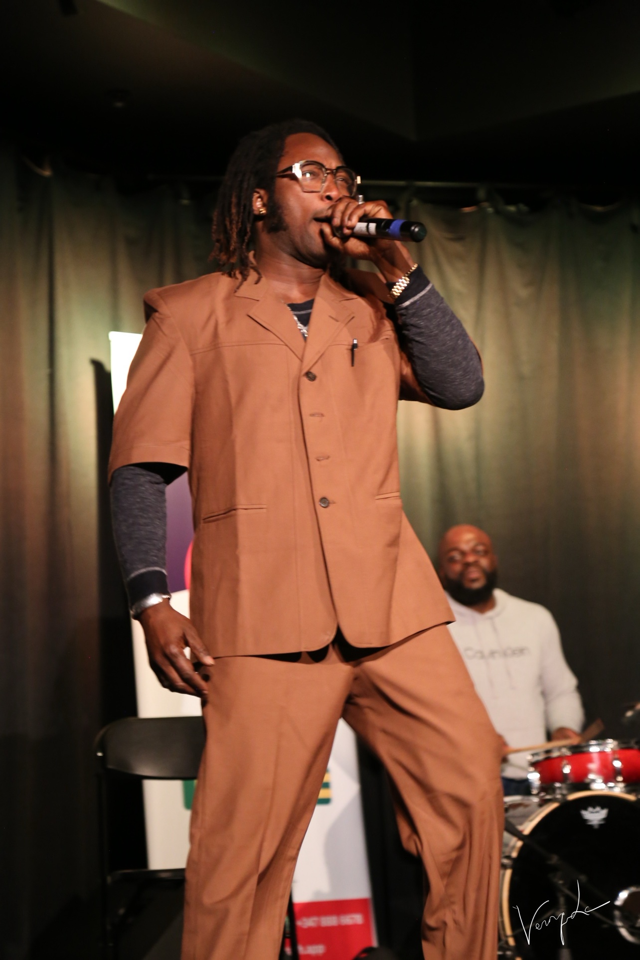 The singer in a brown ensemble, in full performance
