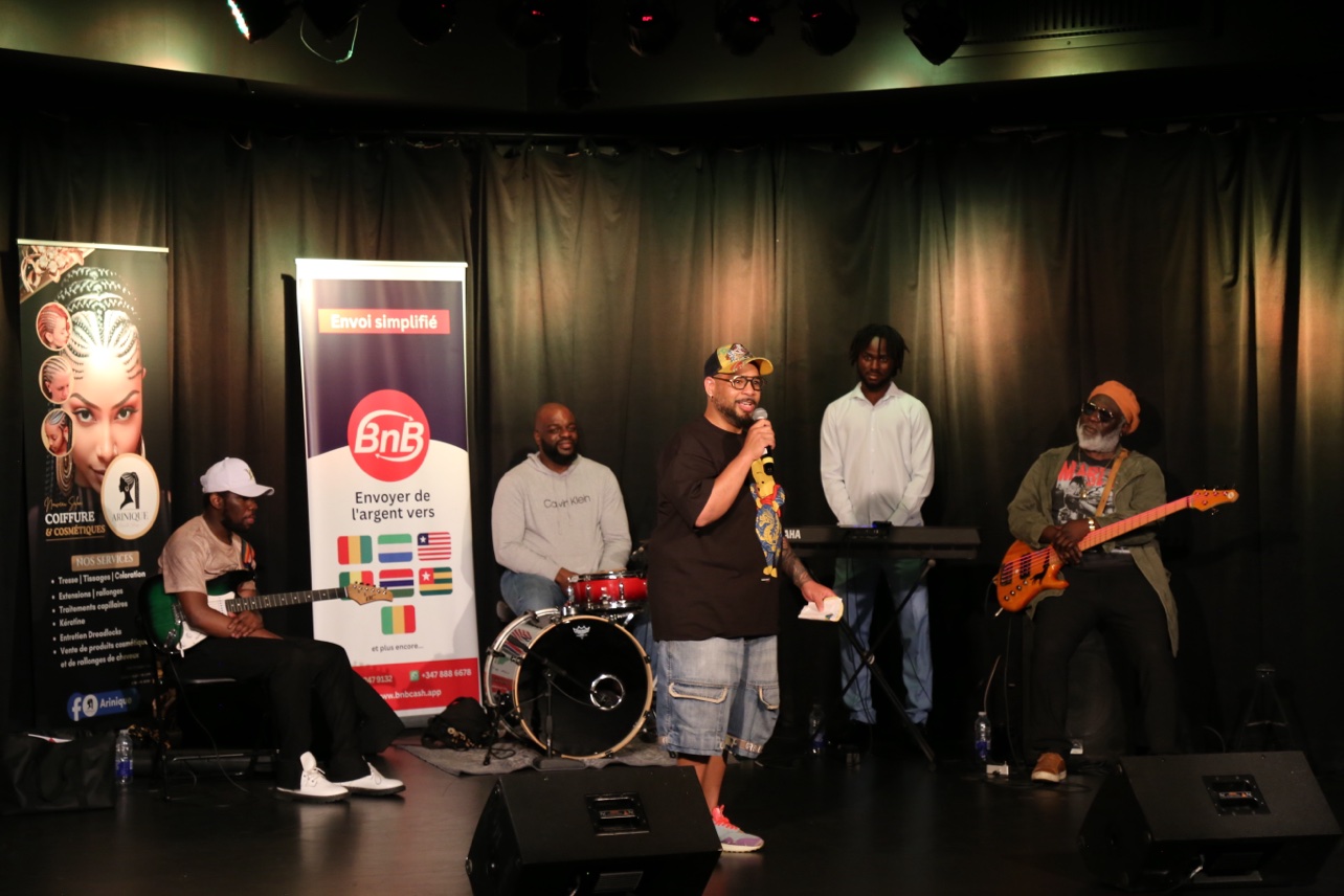 The entire band on stage, between the banners of the partners