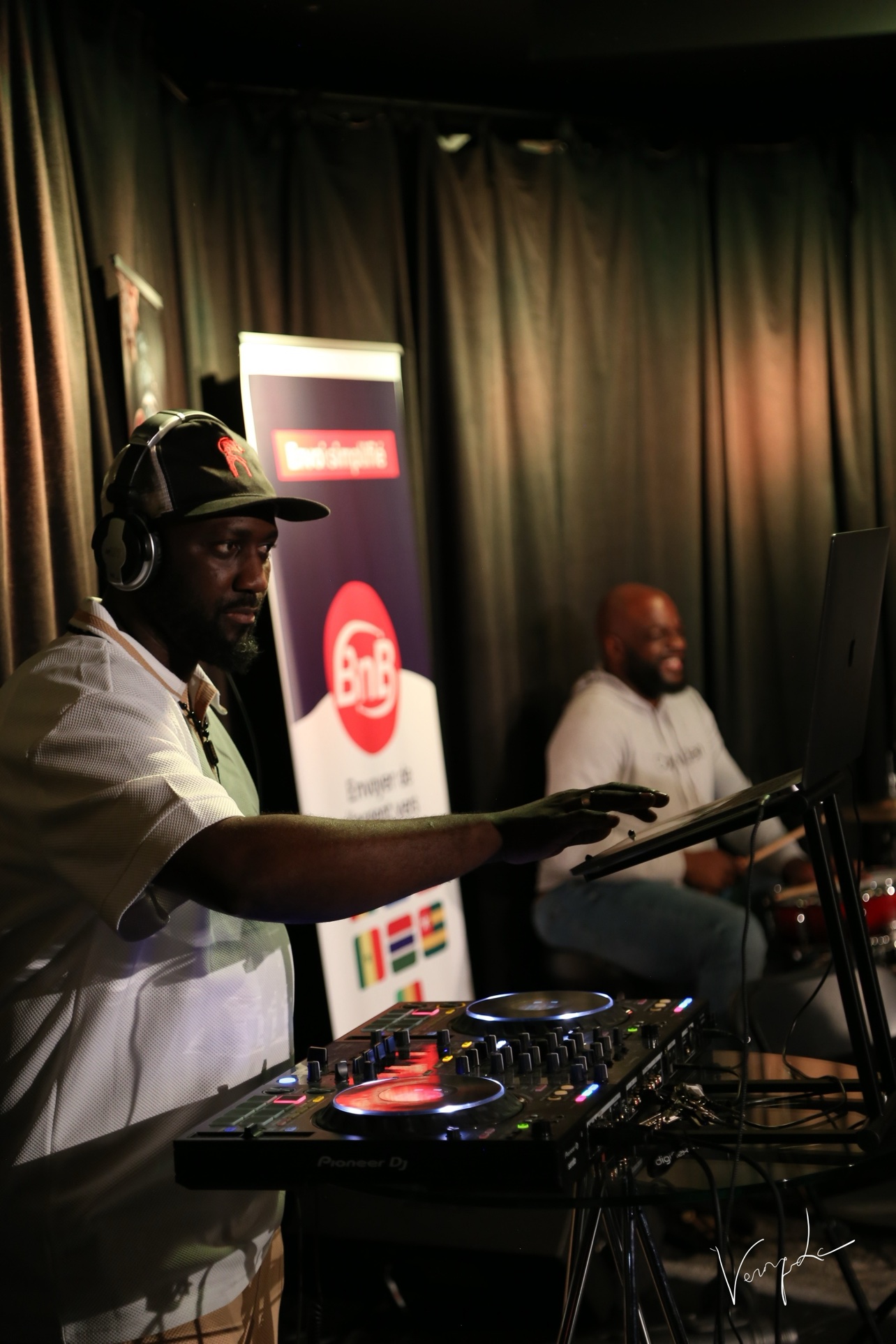 The DJ at the Platinums, in front of the banner of a partner of the evening