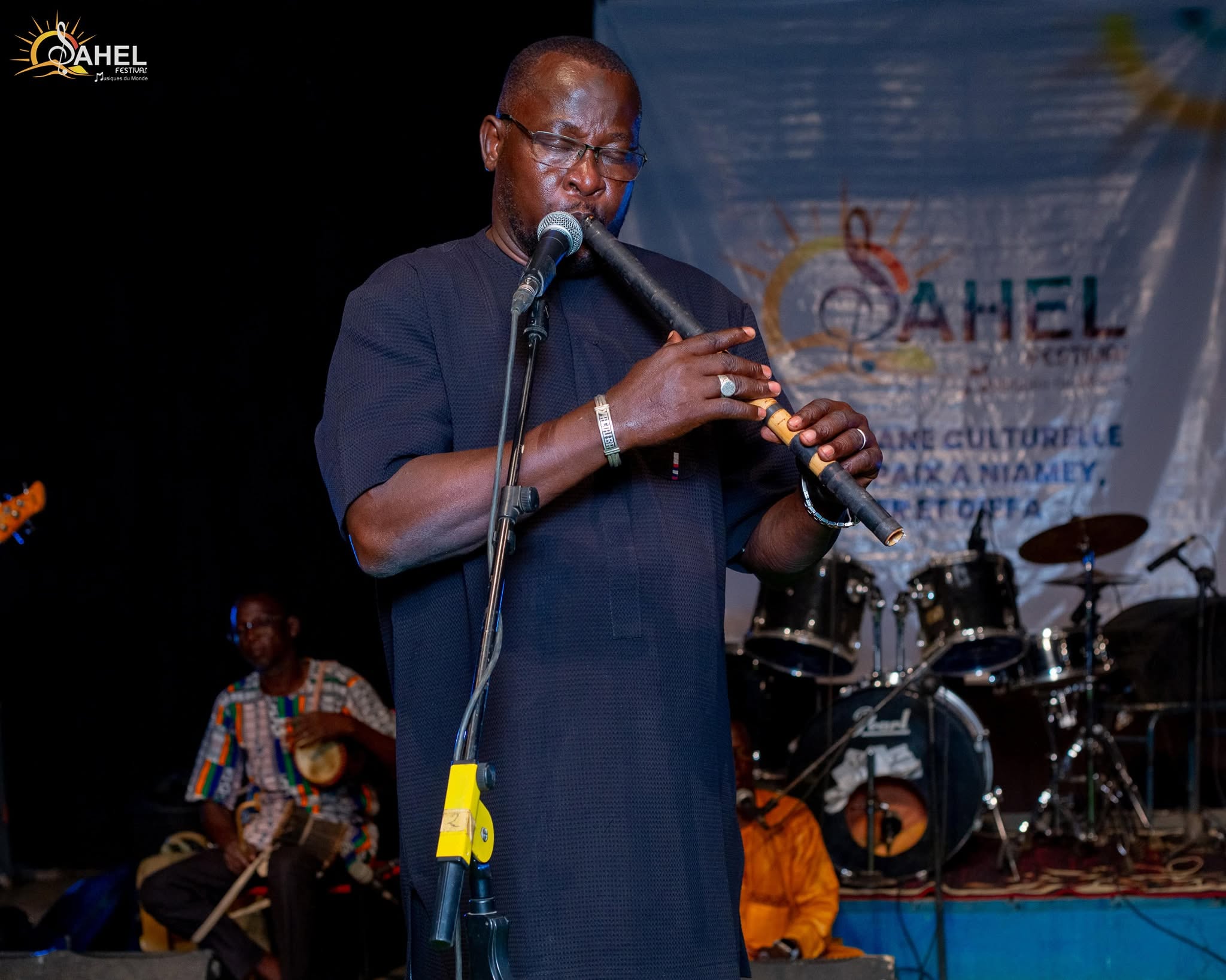 Flutist on the stage of the Sahel Festival in front of the banner of the cultural caravan for peace