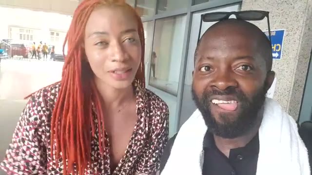 Moïse 1er en mode presse, casque au cou, en selfie avec une invitée devant le fond « les industries culturelles et créatives » en Côte d'Ivoire — captation réelle Festival TV